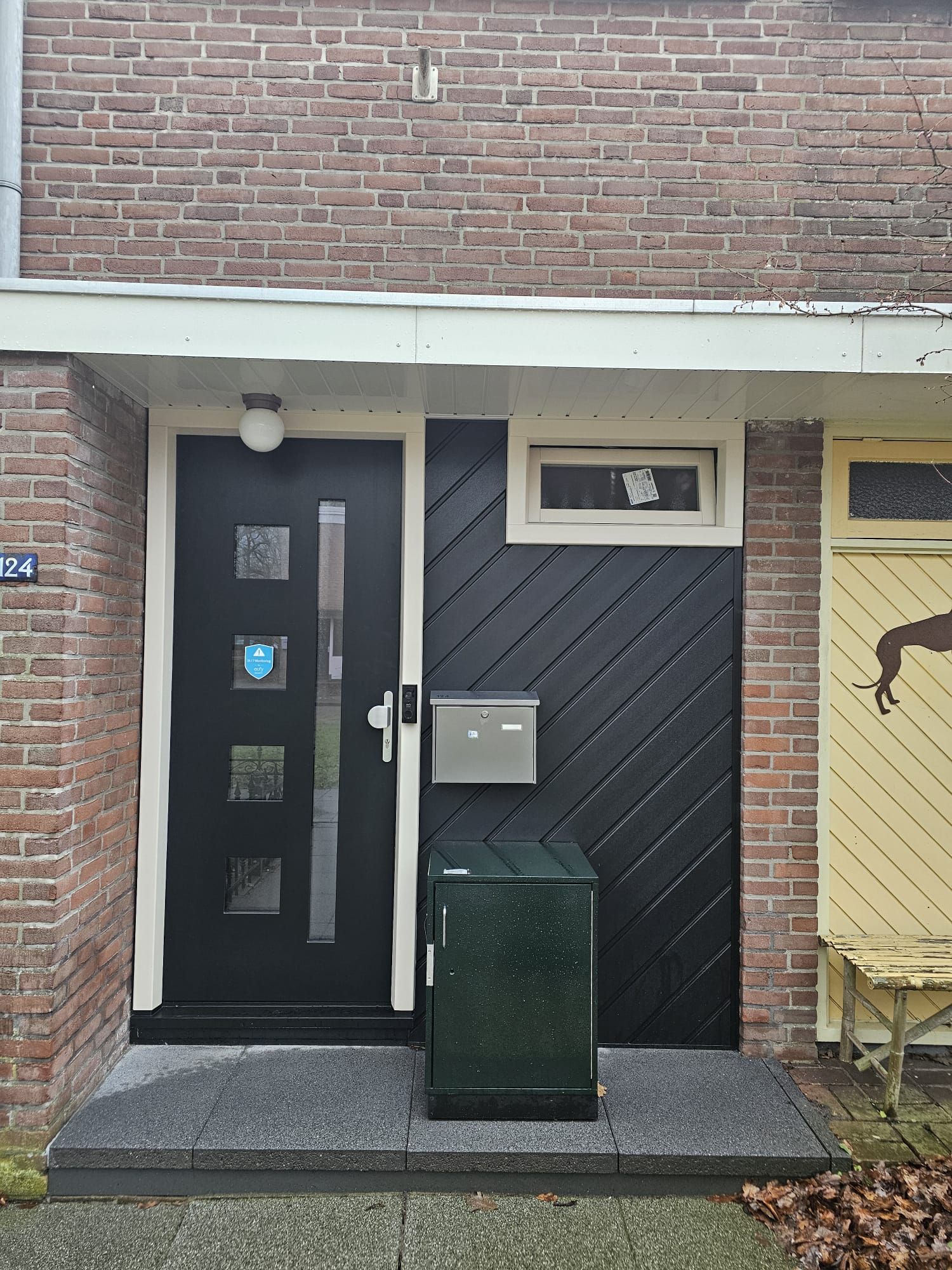 Antraciet kunststof voordeur met zijraam in een rijtjeswoning