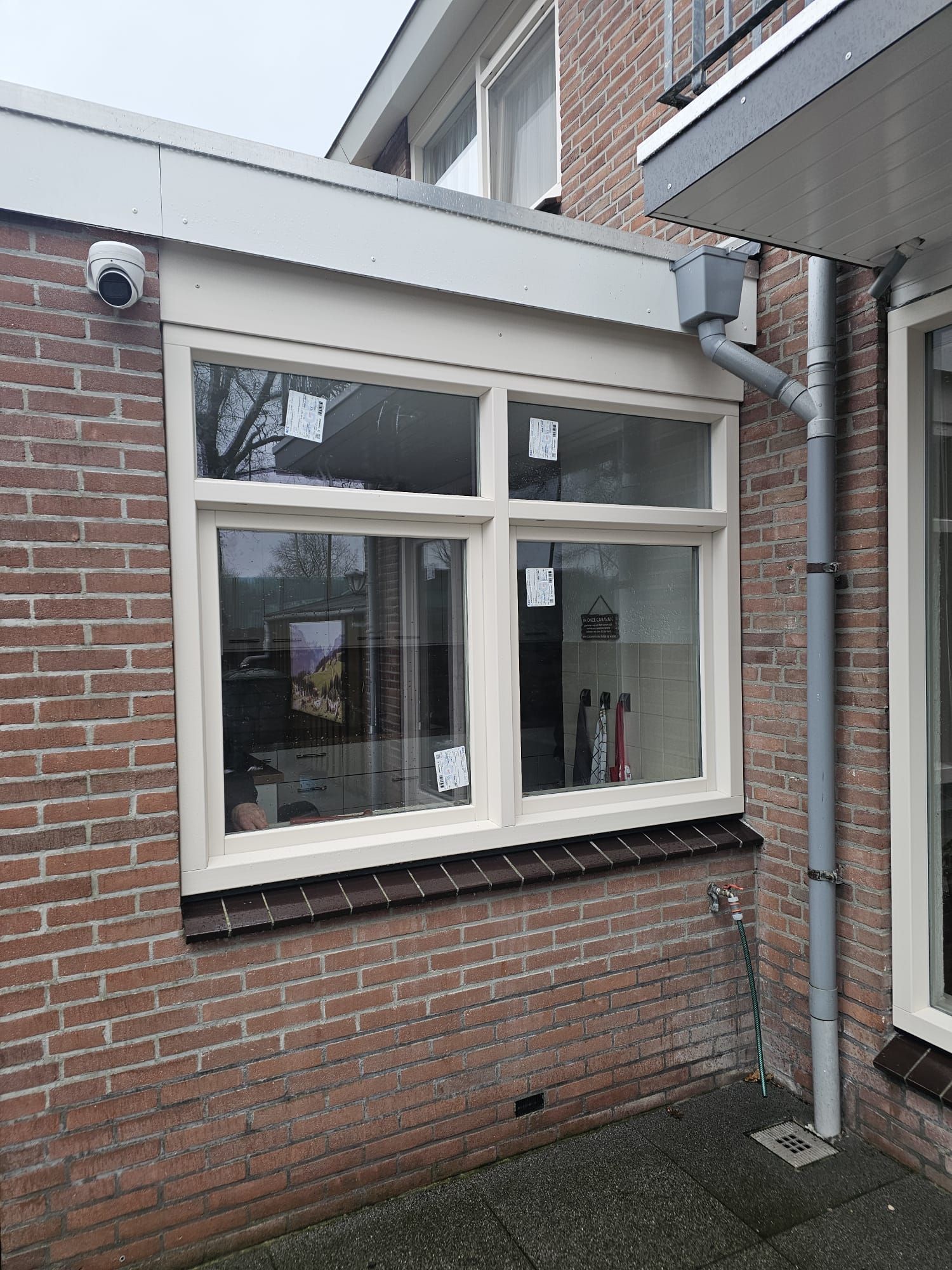 Wit kunststof draaikiepraam in twee delen, geplaatst in bakstenen gevel